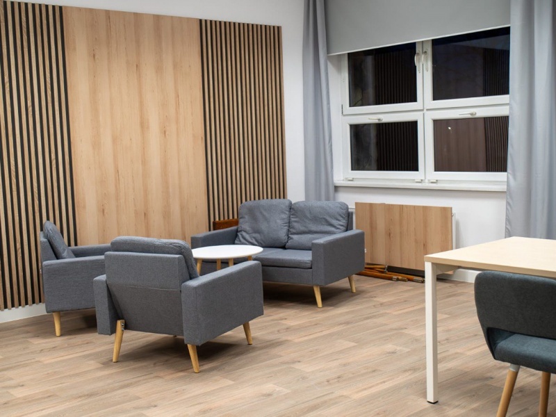 Nowoczesny pokój spotkań z szarymi fotelami, sofą i stolikiem.