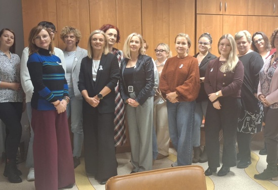 Na zdjęciu znajduje się grupa piętnastoosobowa mająca na sobie przyczepione białe wstążki.