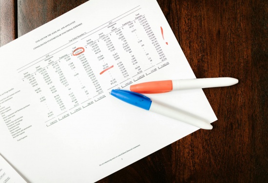 Na zdjęciu jest na stole położony dokument na nim jest coś podkreślone, a  na tym dokumencie znajdują się dwa mazaki w kolorze niebieskim oraz pomarańczowym.