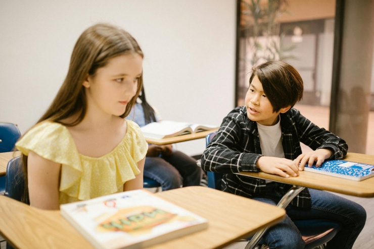 Jeden z uczniów siedzący obok uczennicy rozmawia do niej.